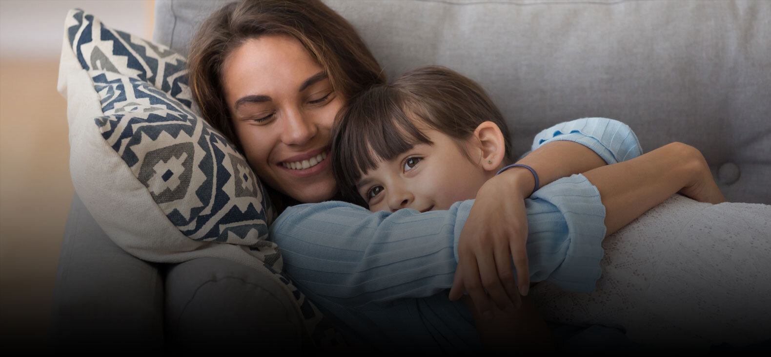 Mother hugging daughter on couch